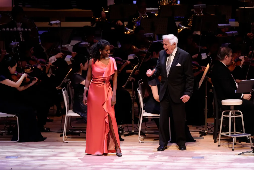 ウィーン国立歌劇場の元総裁、イオアン・ホレンダー（右）が登場。ムゼッタを歌ったマリアム・バッティステッリ（左）もバネのある美しい歌声を聴かせた（C）飯田耕治／東京・春・音楽祭2024