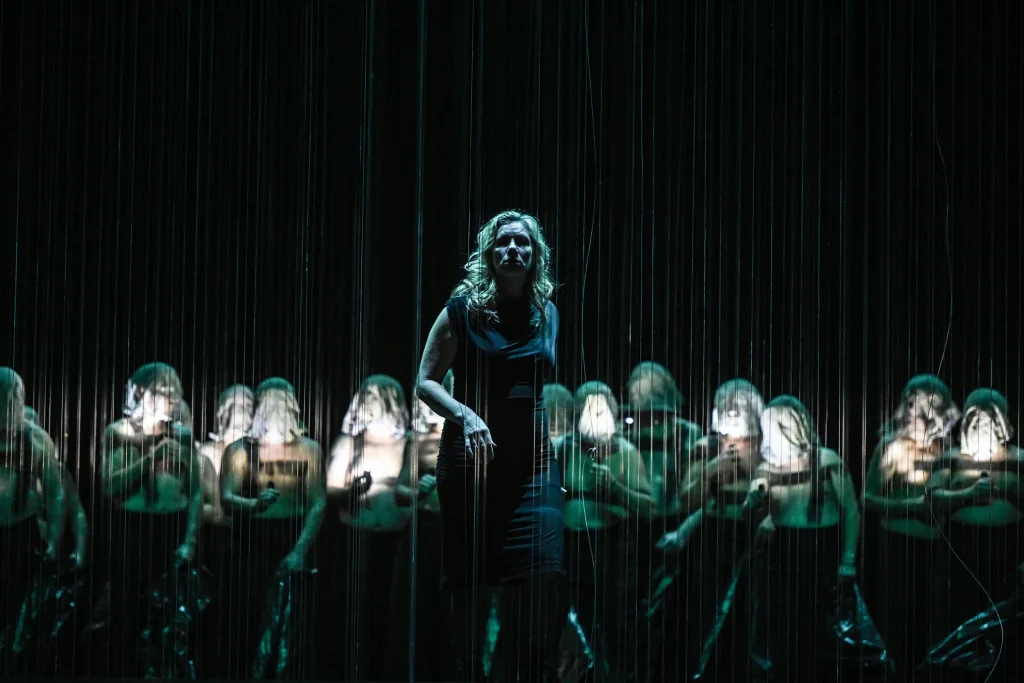 舞台中央から数多くの透明なコードが吊るされ、そこに投影される一本の光の筋で船が表現された　(c) Hans Jörg Michel