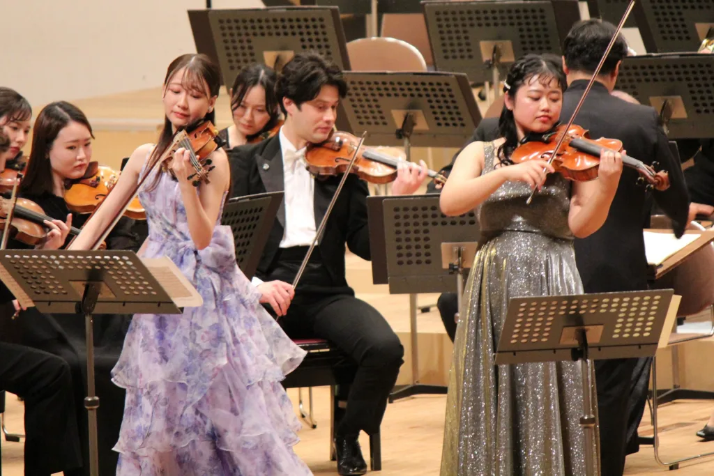 和田一樹指揮、新日本フィルをバックに伸びやかなソロで聴衆を魅了した若手ヴァイオリニストの平井美羽（中央左）、ウィーン・フィル アカデミー修了生のヴィオラ奏者・有冨萌々子（同右）　写真提供＝なかのZEROホール